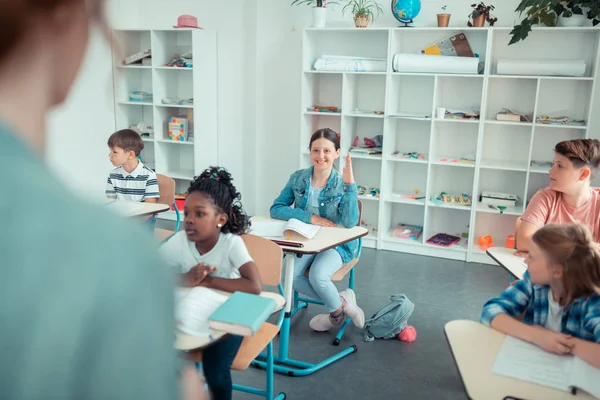 Ragazza della scuola alzando la mano per rispondere alla domanda del suo insegnante . — Foto Stock