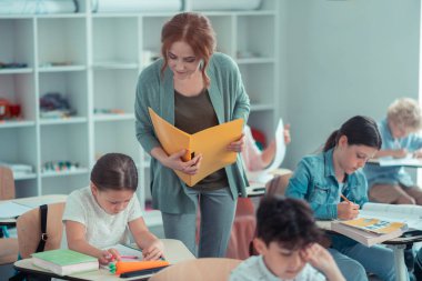 Öğrencilerine yakından bakan özenli öğretmen çalışıyor.