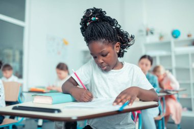 Schoolgirl testte konsantre yüz ile toplamları yapıyor .