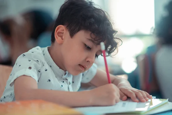 School jongen schrijven zijn test tijdens de les. — Stockfoto