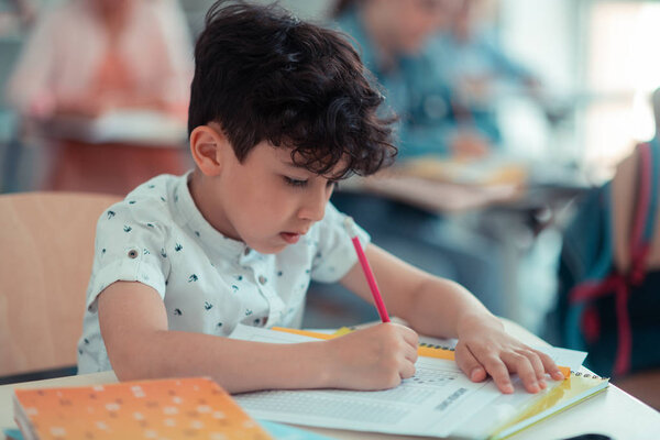 Concentrated pupil completing his test in class.