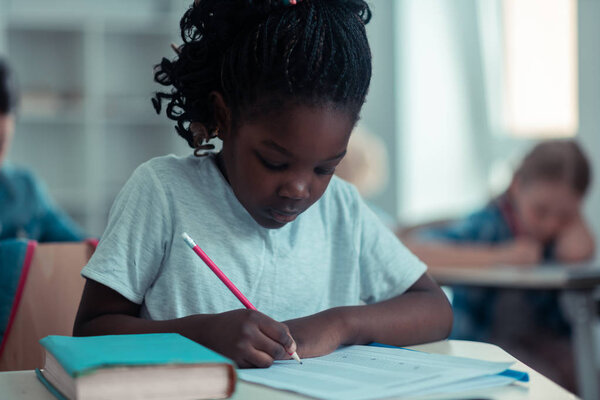 Focused little girl writing her school test.