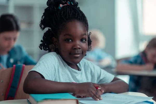 Ładna Szkoła dziewczyna uśmiechnięta siedzi na lekcji. — Zdjęcie stockowe