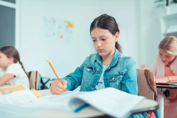Menina da escola olhando ansiosamente para o seu teste de matemática . — Fotografia de Stock