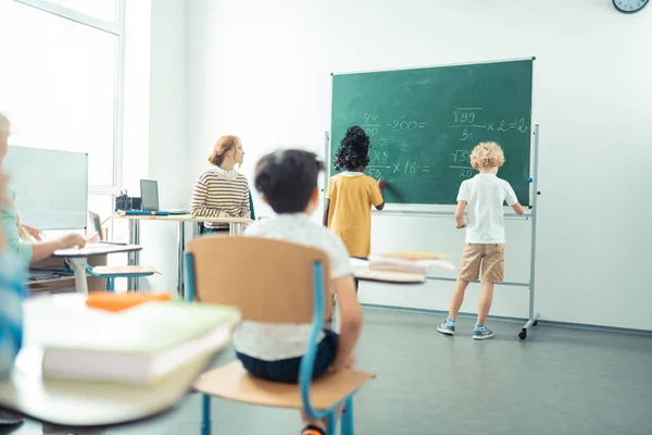 Two classmates writing together on the blackboard. — Stock Photo, Image