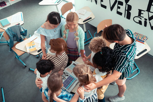 School children forming a circle around their teacher.