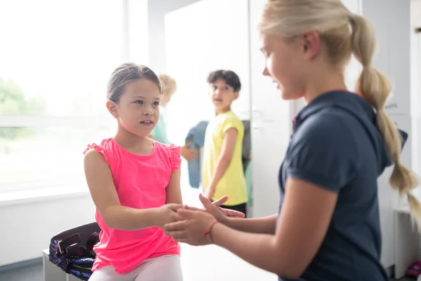 Two girls playing patty-cake near their classmates. — Stock Photo, Image