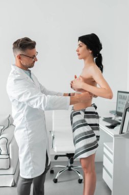 Çıplak göğüslü koyu saçlı kadın plastik cerrahı ziyaret ediyor