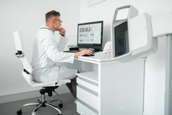 Professioneller plastischer Chirurg sitzt während der Arbeit am Computer — Stockfoto