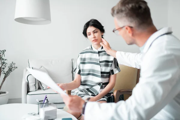 Chirurg in glazen aanraken gezicht van de cliënt voor plastische chirurgie — Stockfoto