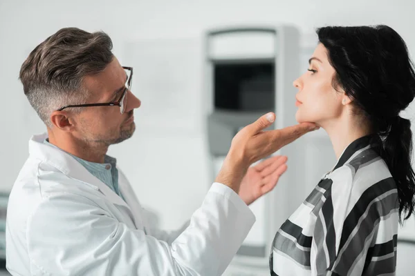 Ervaren cosmetica chirurg onderzoekt gezicht van mooie vrouw — Stockfoto