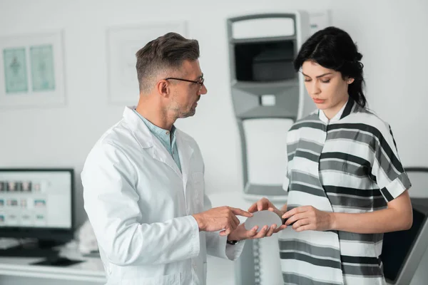 Plastic surgeon wearing glasses showing client implants for breast — Stock Photo, Image