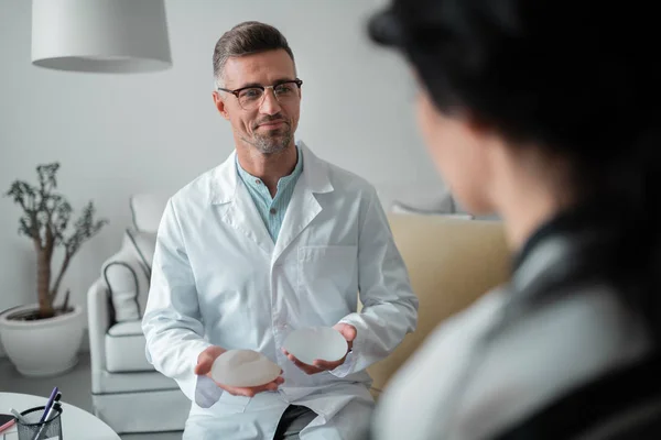 Schönheitschirurg trägt Brille mit Brustimplantaten — Stockfoto