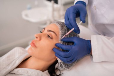 Güzellik kliniğiziyaret güzellik enjeksiyonları olan koyu gözlü kadın