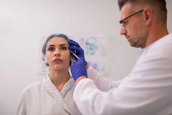 Skäggiga läkare bär glasögon gör Botox injektioner — Stockfoto