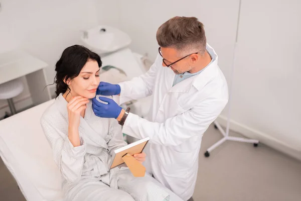 Belle femme regardant dans le miroir après la chirurgie — Photo