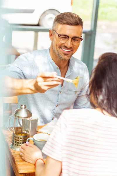 Smiling man sharing his food with his wife. — Stock Photo, Image