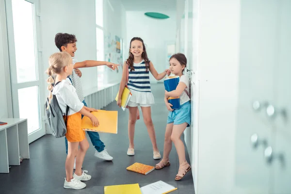 Грубі діти кидають папери дівчини на підлогу, знущаючись над нею — стокове фото