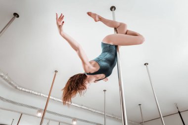 Kutup dansçısı üzerinde alt görünümü egzersizleri yapıyor.