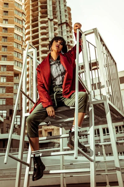 Atractiva mujer internacional sentada en las escaleras —  Fotos de Stock