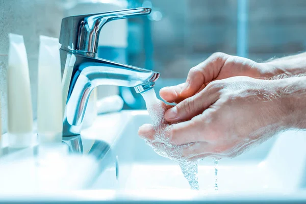 Guy with strong hands watering palms in a bathroom