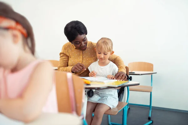 Dark-skinned teacher feeling happy working with children