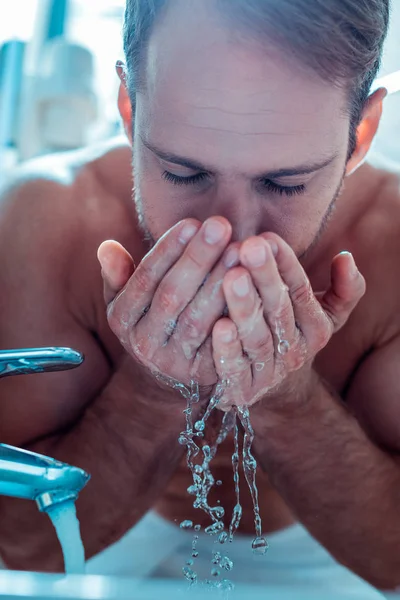 Aufmerksamer kurzhaariger Mann benetzt Gesicht in Waschbecken — Stockfoto