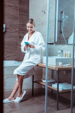 Rahat bir ev giymek gülümseyen bayan bir lavabo yaslanmış