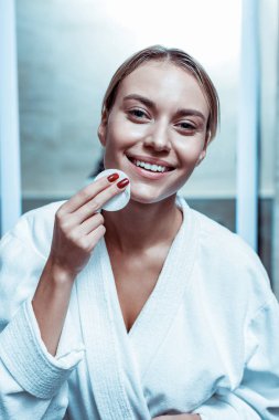 Toner ile pamuk ped tutan beyaz dişleri ile Gülen çekici kadın