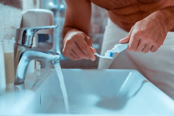 Aufmerksame Person drückt Zahnpasta auf eine Bürste — Stockfoto