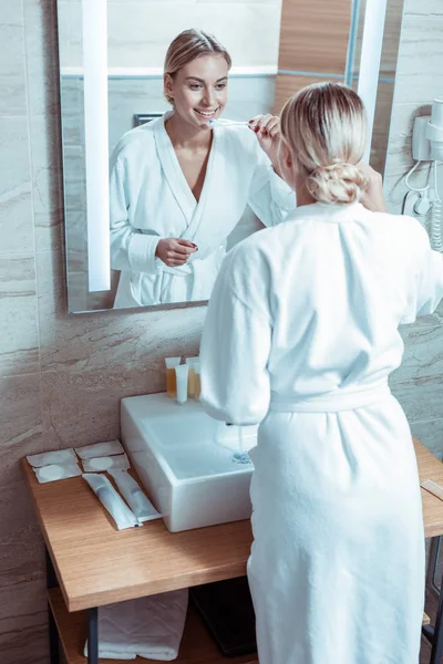 Bella signora con i capelli legati stare davanti allo specchio — Foto Stock