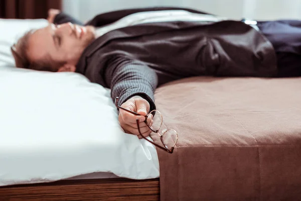 Hombre de pelo corto cansado acostado en la cama con un disfraz —  Fotos de Stock