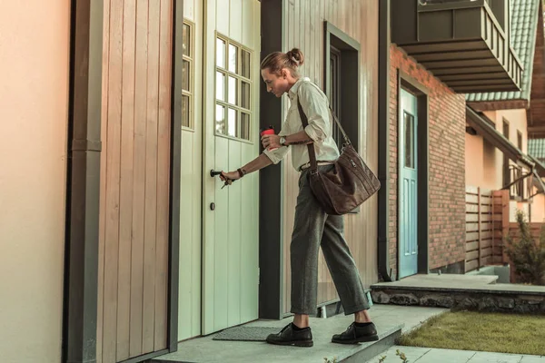 Blonde good-looking guy in office outfit carrying leather bag o the shoulder