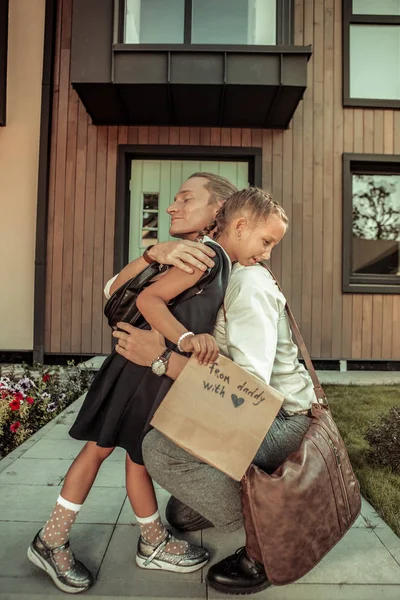学校の日の前に若い娘をしっかりと抱きしめるポジティブなお父さんを思いやり — ストック写真
