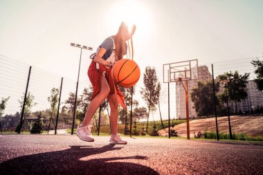 Turuncu topu ısıran esnek spor ayakkabılı odaklanmış deneyimli kız