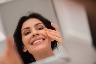 Estetik ameliyat tan sonra yüzüne dokunan memnun kadın