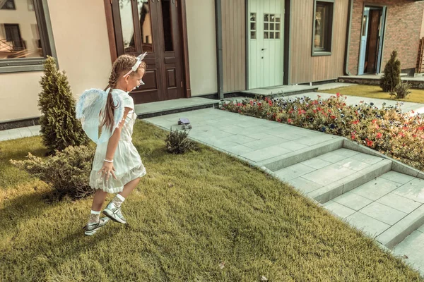 밝은 의상을 입고 녹색 잔디밭을 걷는 활동적인 예쁜 소녀 — 스톡 사진