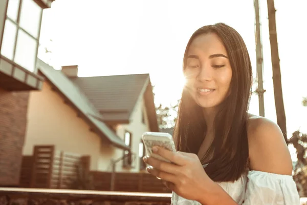 Mujer bastante morena con una sonrisa suave revisando las redes sociales — Foto de Stock