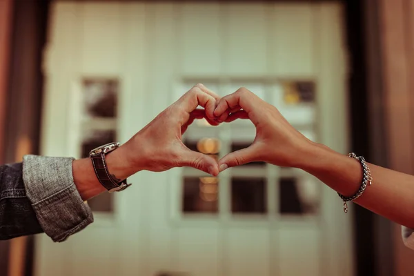 Pareja positiva conectando los dedos y creando forma de corazón — Foto de Stock