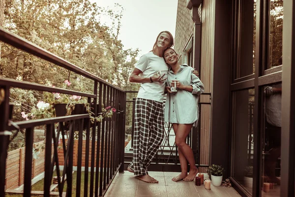 Beaming positive guys leaning on the metal railing of the balcony — Stock Photo, Image