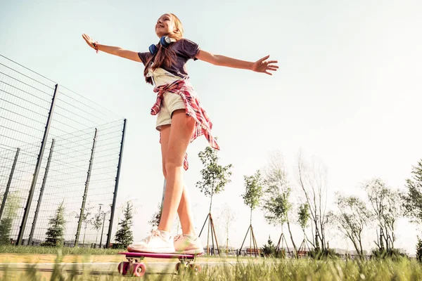 Активна маленька дівчинка в футболці і шортах, що залишаються на скейтборді — стокове фото