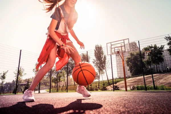 Doświadczony Ciemnowłosa młoda dziewczyna działa wokół boisko do koszykówki — Zdjęcie stockowe
