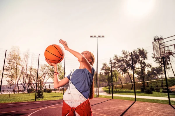 Envolvido menina esportiva de cabelos escuros melhorar suas habilidades no jogo de basquete — Fotografia de Stock