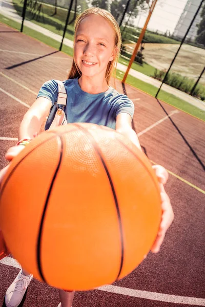 Sorrindo bonito jovem senhora apresentando sua nova bola laranja — Fotografia de Stock