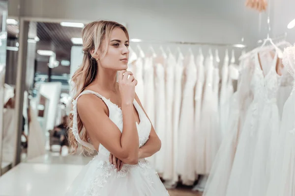 Молодая невеста смотрит свадебные платья в магазине . — стоковое фото
