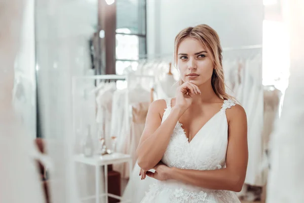 Fiatal nő egy esküvői ruha keres átgondolt. — Stock Fotó