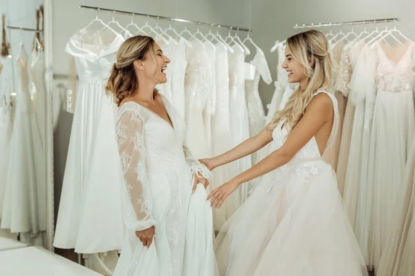 Two beautiful brides laughing in a wedding salon.