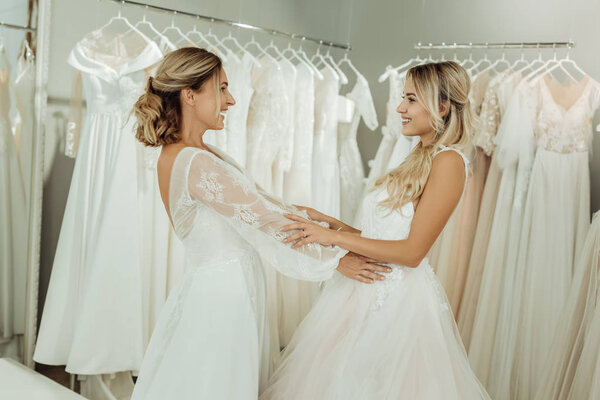 Two friends trying on wedding dresses together.