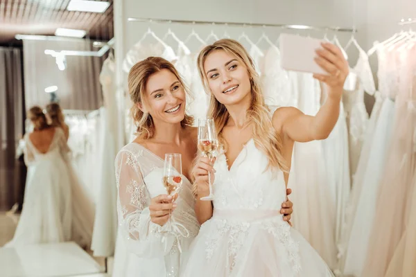 Duas noivas tomando uma selfie em um salão de casamento . — Fotografia de Stock