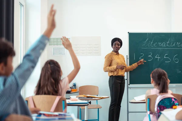 Dunkelhäutige Lehrerin gibt die Frage an ihre intelligenten Schüler — Stockfoto